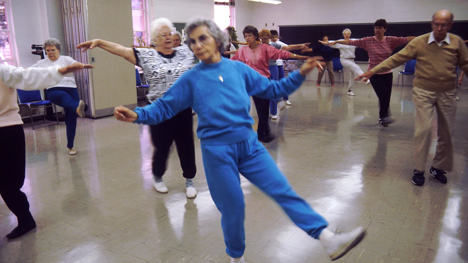 A bright, active group of older adults taking part in a wellness exercise class